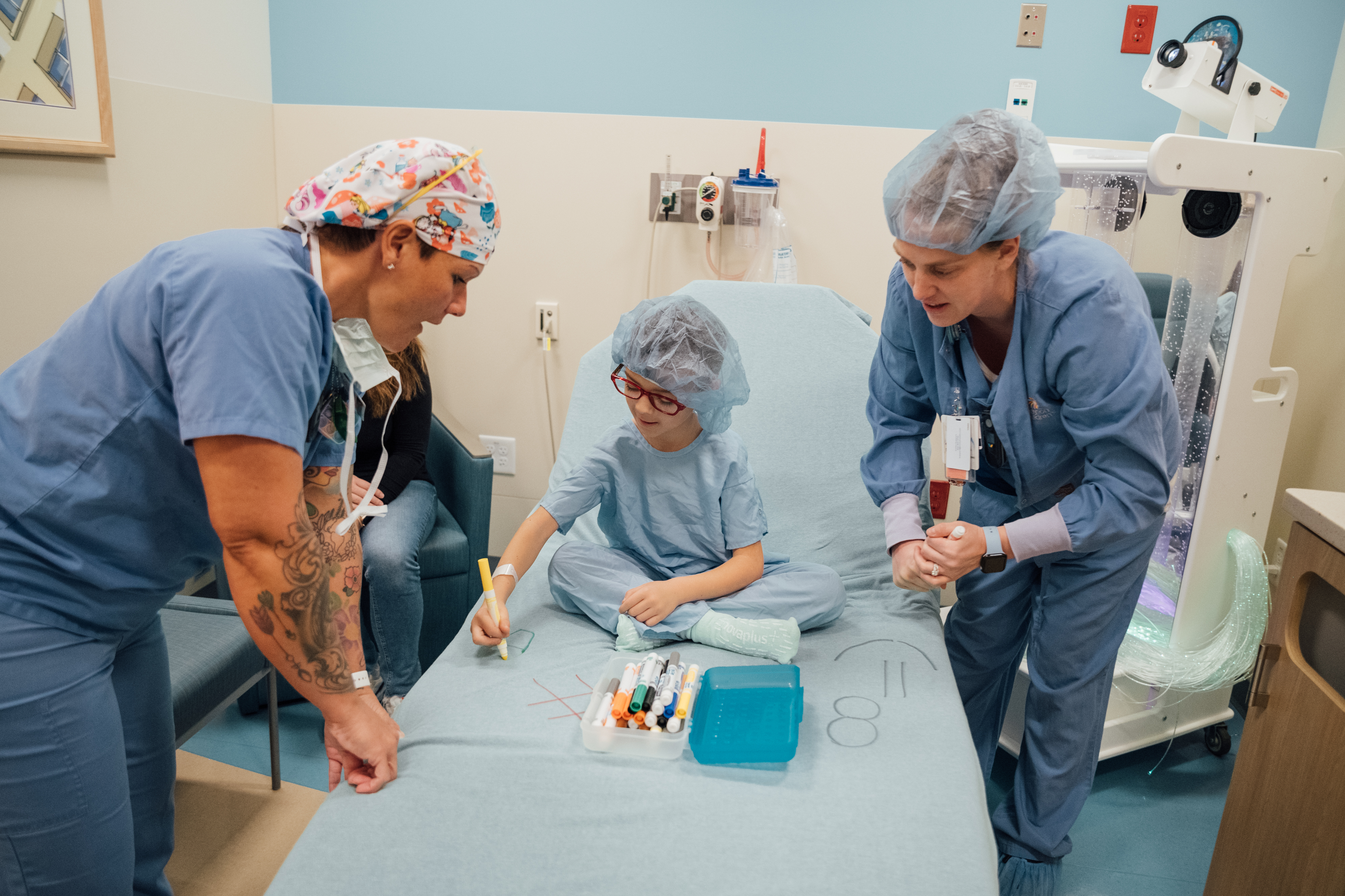 little boy in surgery gown coloring on bed