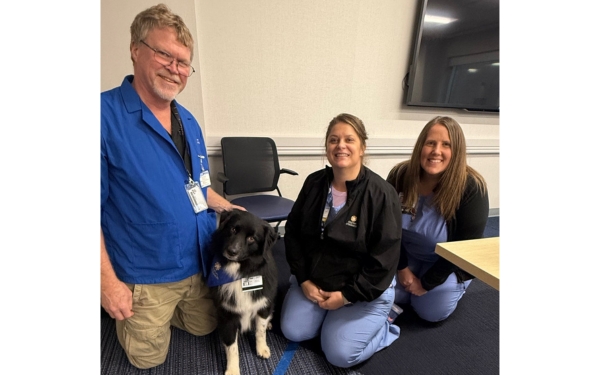 pet therapy volunteer with dog and 2 employees