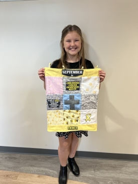 Charlotte with a quilt she made for fundraising at the Gala of Hope