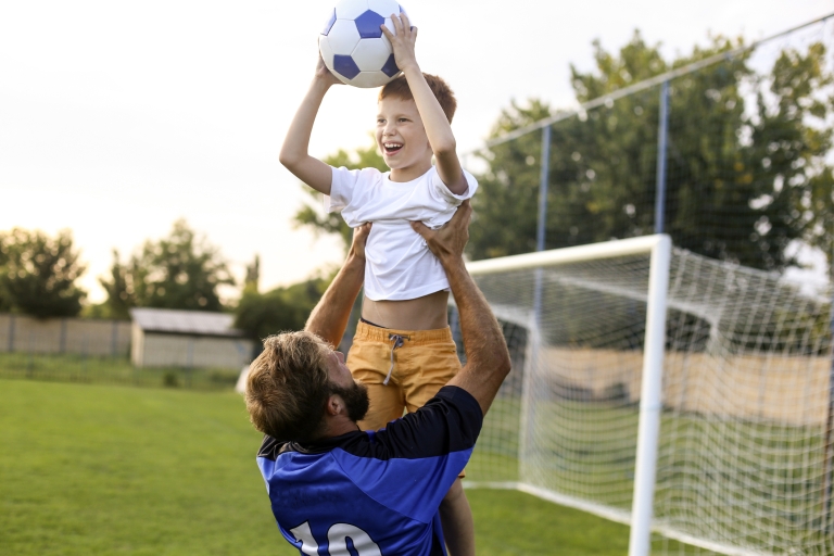 father and son playing soccer outdoors