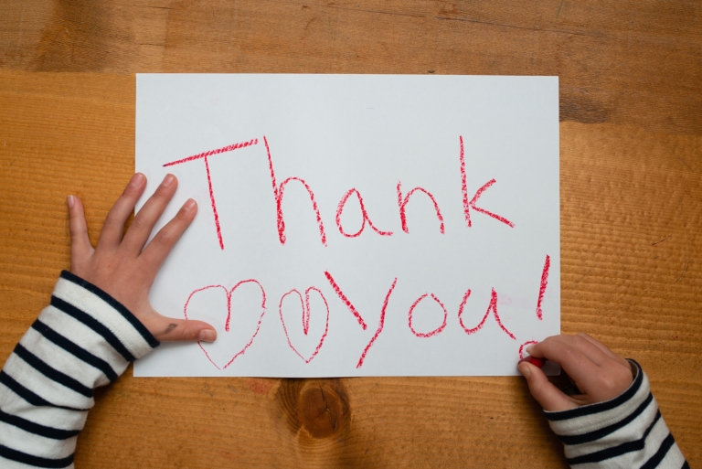 child writing thank you on a piece of paper