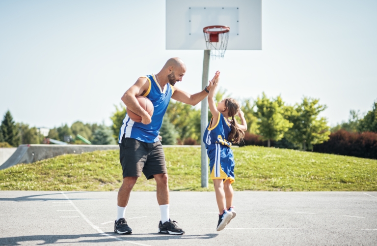 father and daughter playing basketball