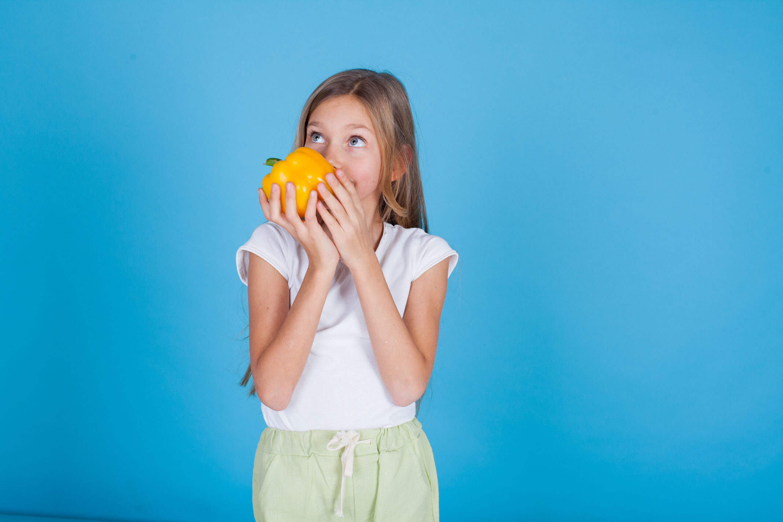 Young girl holds a yellow pepper vegetable