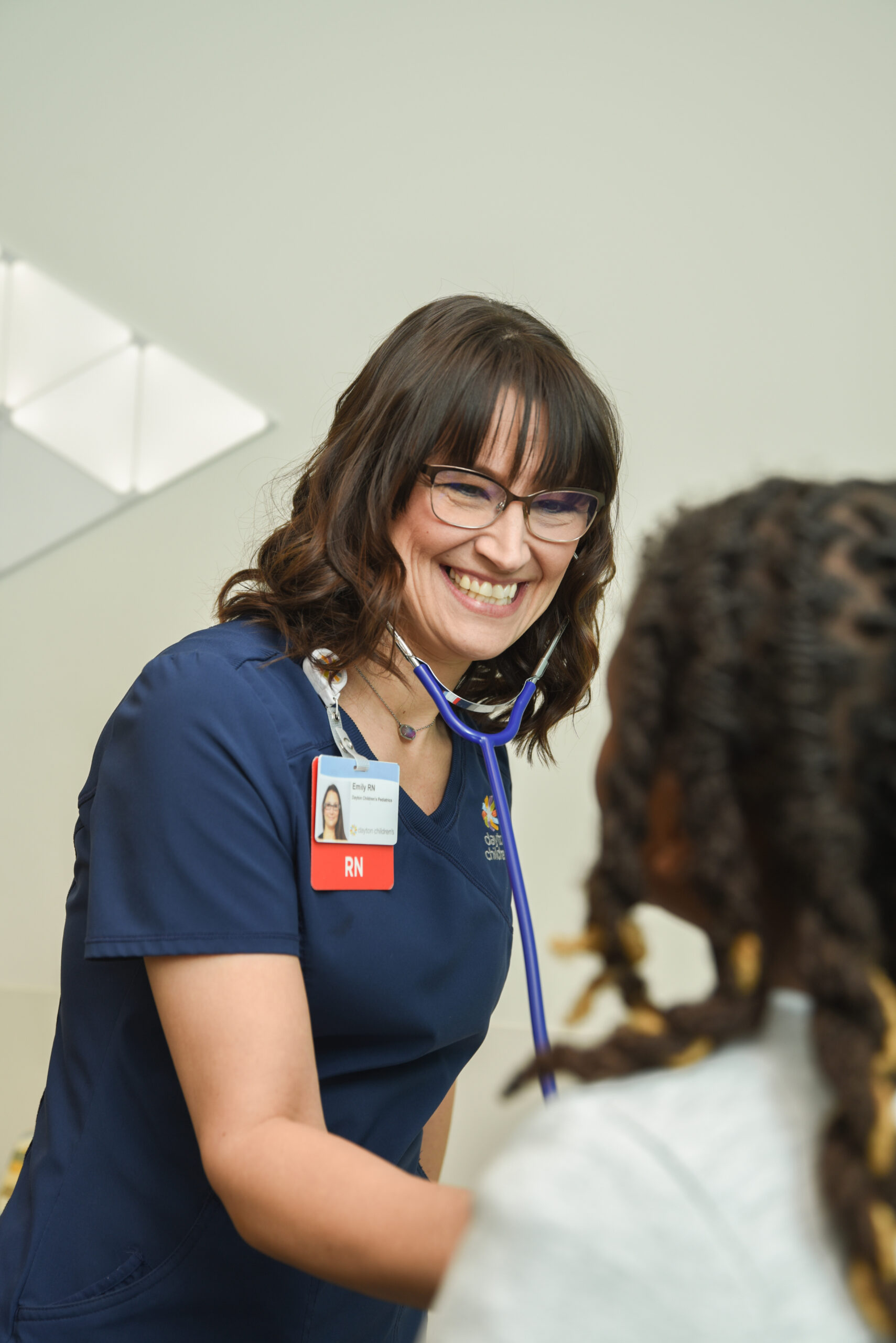 A pediatric nurse speaks warmly with a young patient, reflecting the dedication and compassion highlighted in the annual nursing report.