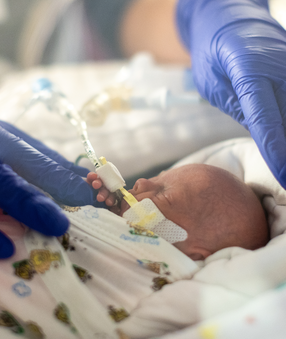 Little baby being swaddled gently by caregiver.
