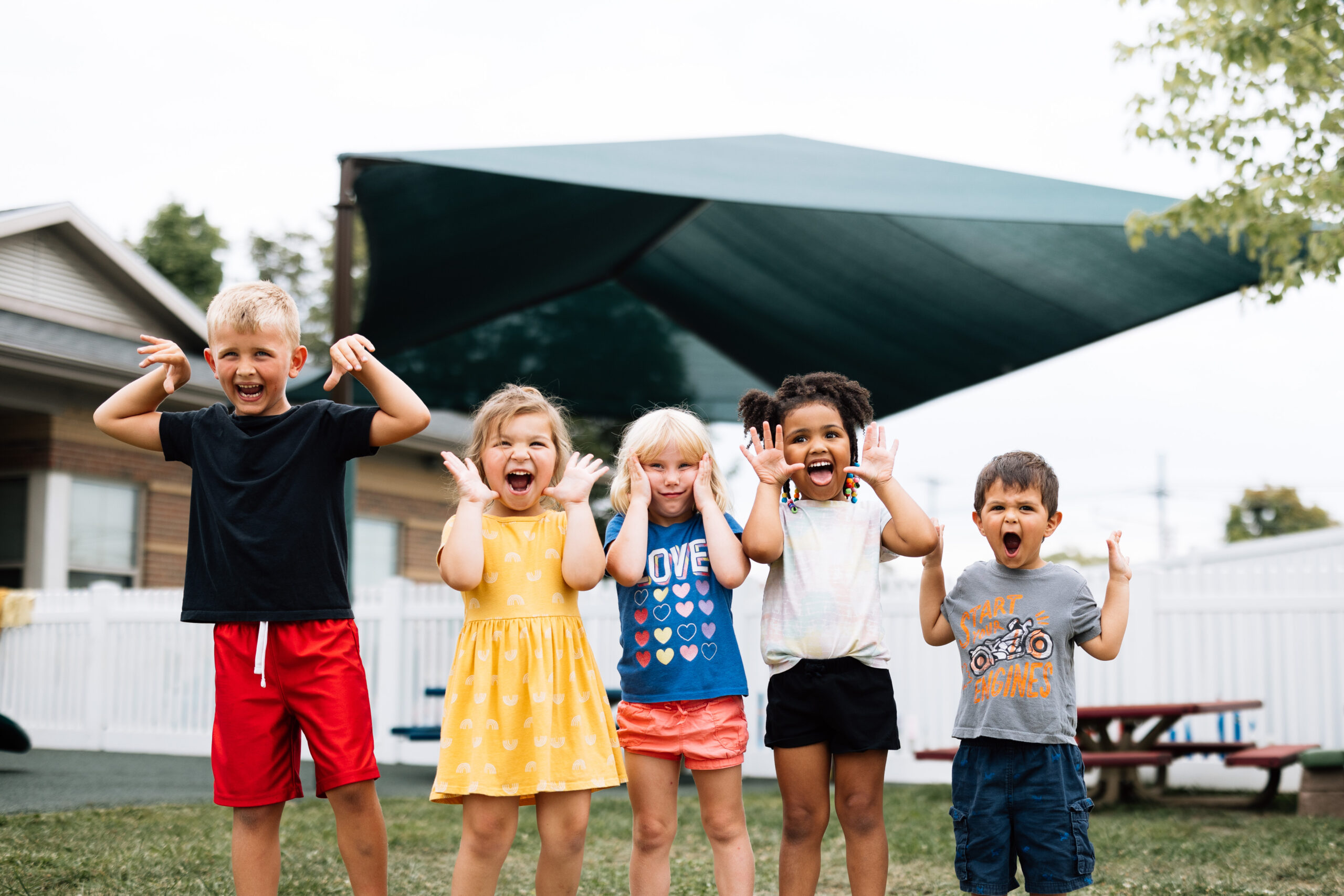 A group of smiling children participates in an outdoor community event, symbolizing outreach and impact featured in the community benefit report.