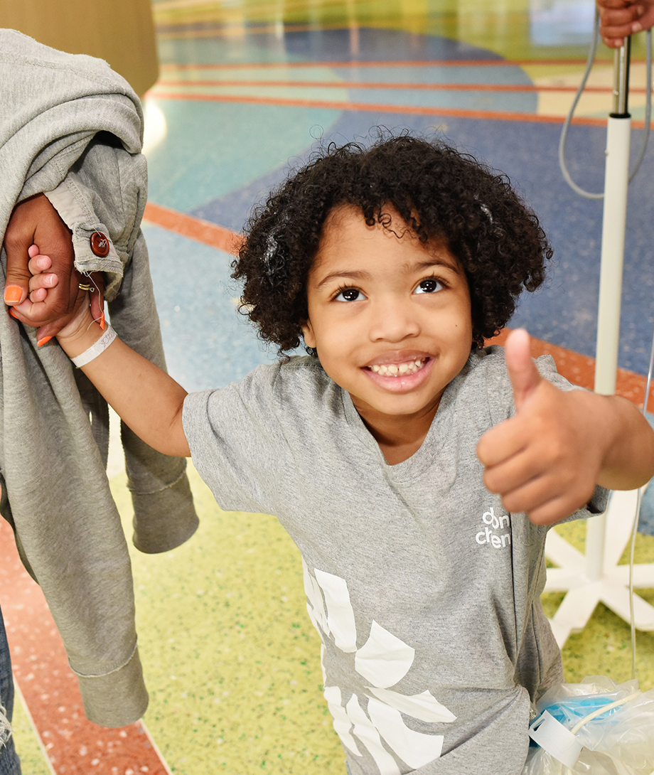 Smiling child giving a thumbs up while holding a caregiver’s hand at Dayton Children’s Hospital