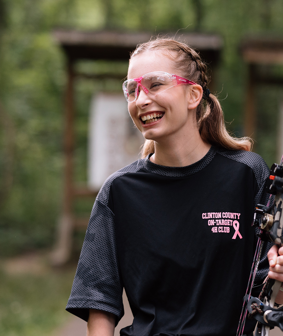 Teen patient smiling outdoors while holding a bow.