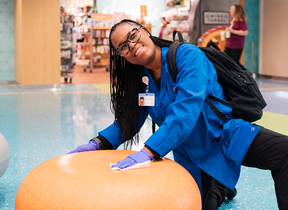 Teenage volunteer sanitizes furniture at the hospital to ensure safety of patients and families.