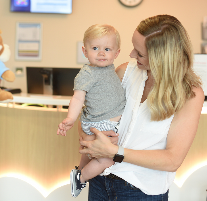 Mother holding young child at the check-in desk at Dayton Children’s Hospital before their visit.