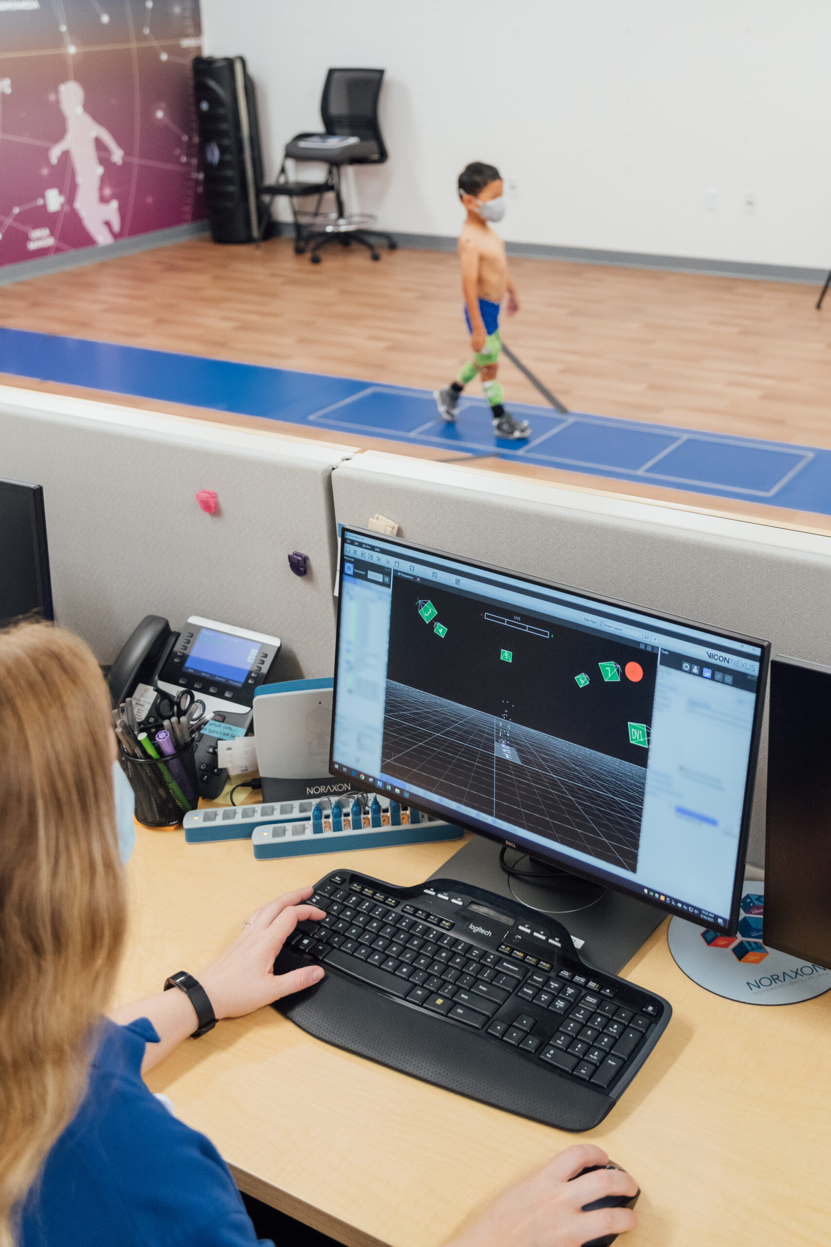The gait lab team conducts gait and motion analysis on a computer while the child walks with sensors attached to his body. 