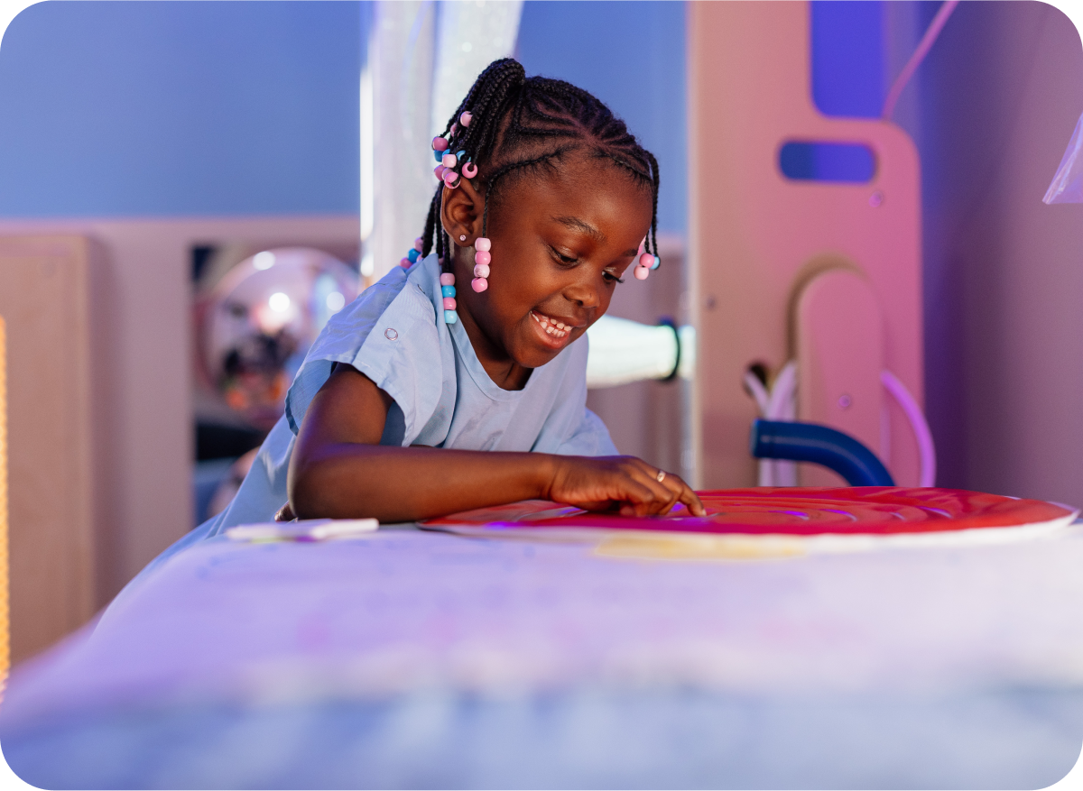 Young patient smiling and drawing during an art activity at Dayton Children’s Hospital, representing the impact of planned giving.