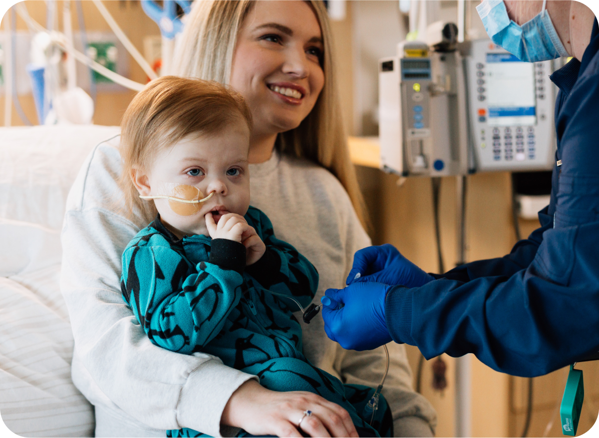  Parent holding young child while a nurse provides care at Dayton Children’s Hospital, supporting the importance of donations.