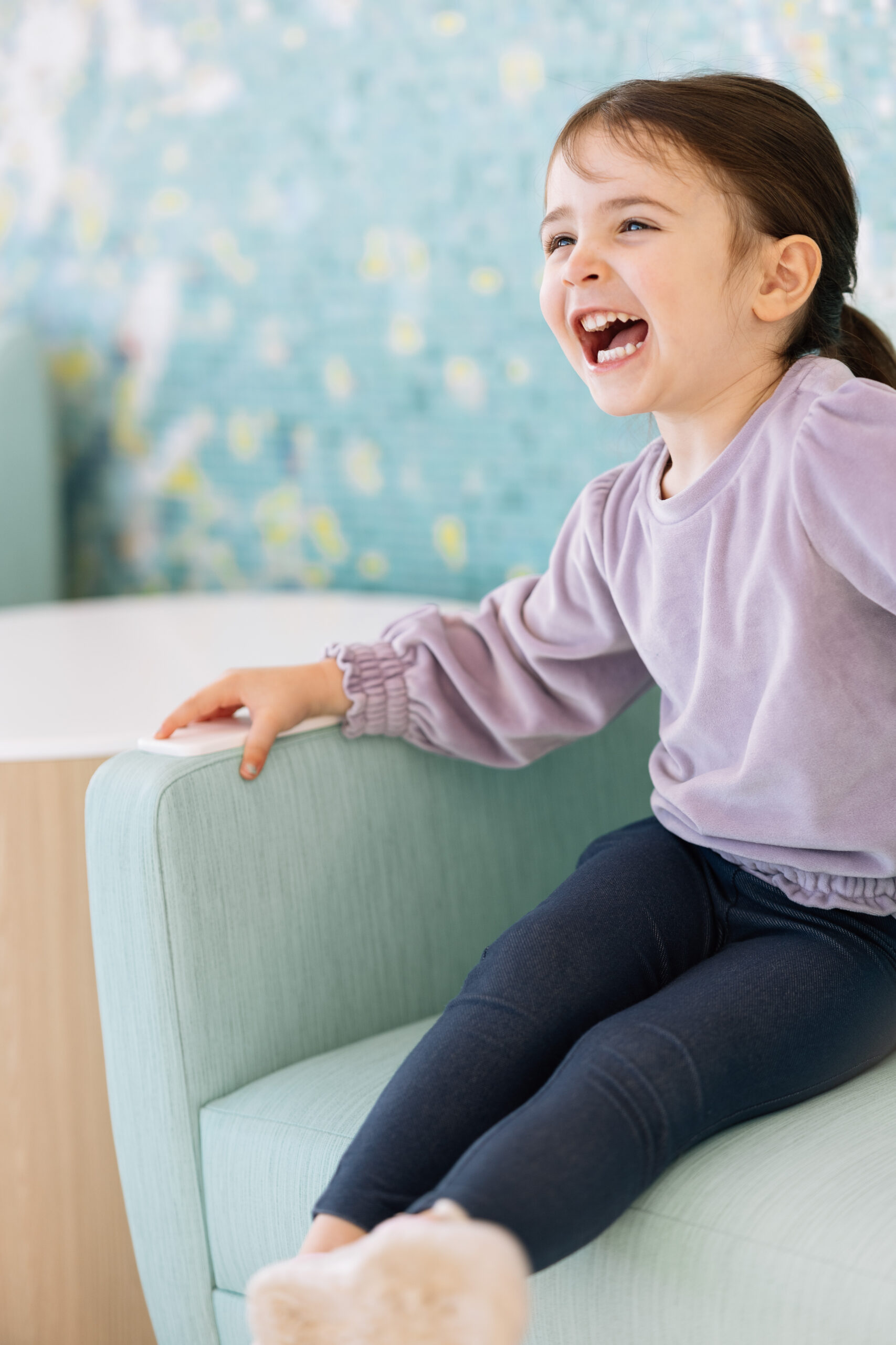 Smiling girl laughing while sitting on a chair
