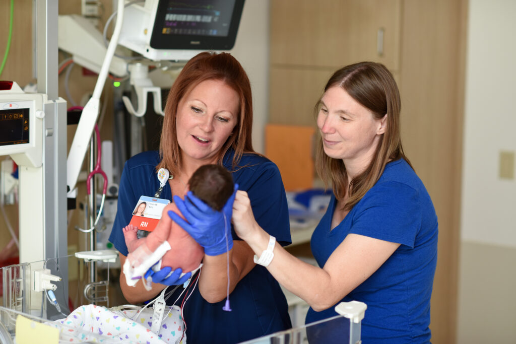 A very young baby in the NICU preparing to be transferred to the TCU by their nurses.