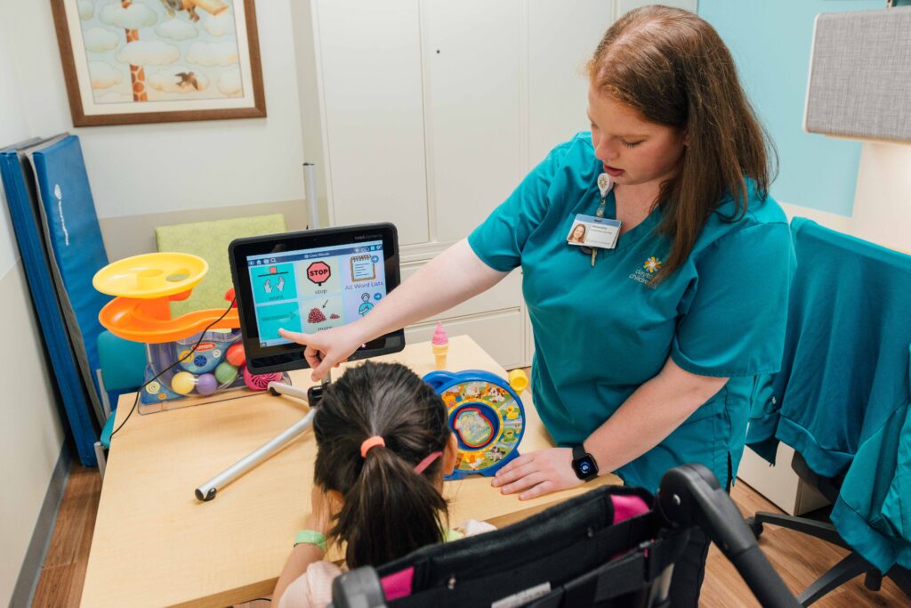 A Dayton Children’s rehab specialist works with a patient to learn how to communicate through a computer.