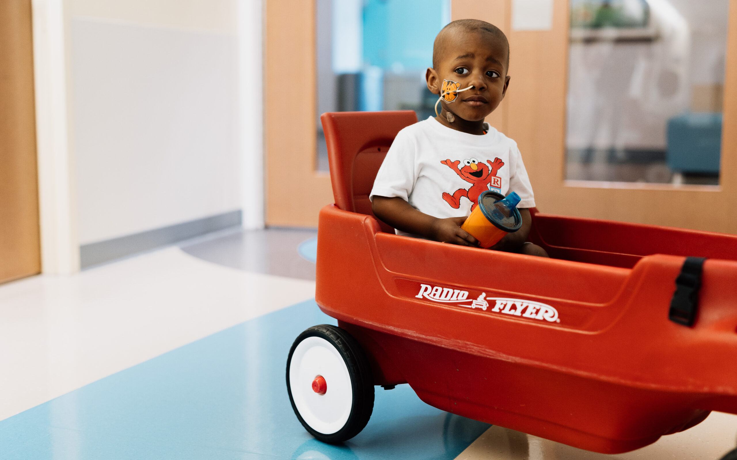 Young child riding in a red wagon as part of Dayton Children’s Hospital wish list program.