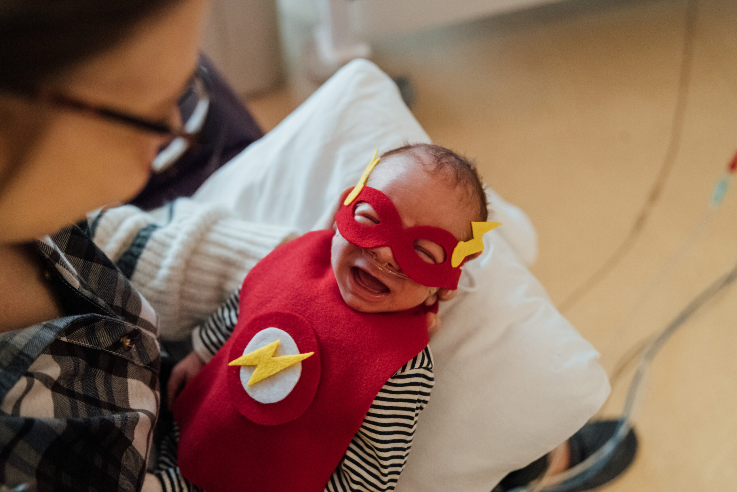 A little baby is dressed up as a super hero with a mask and cape, showing how strong Dayton Children’s patients are!