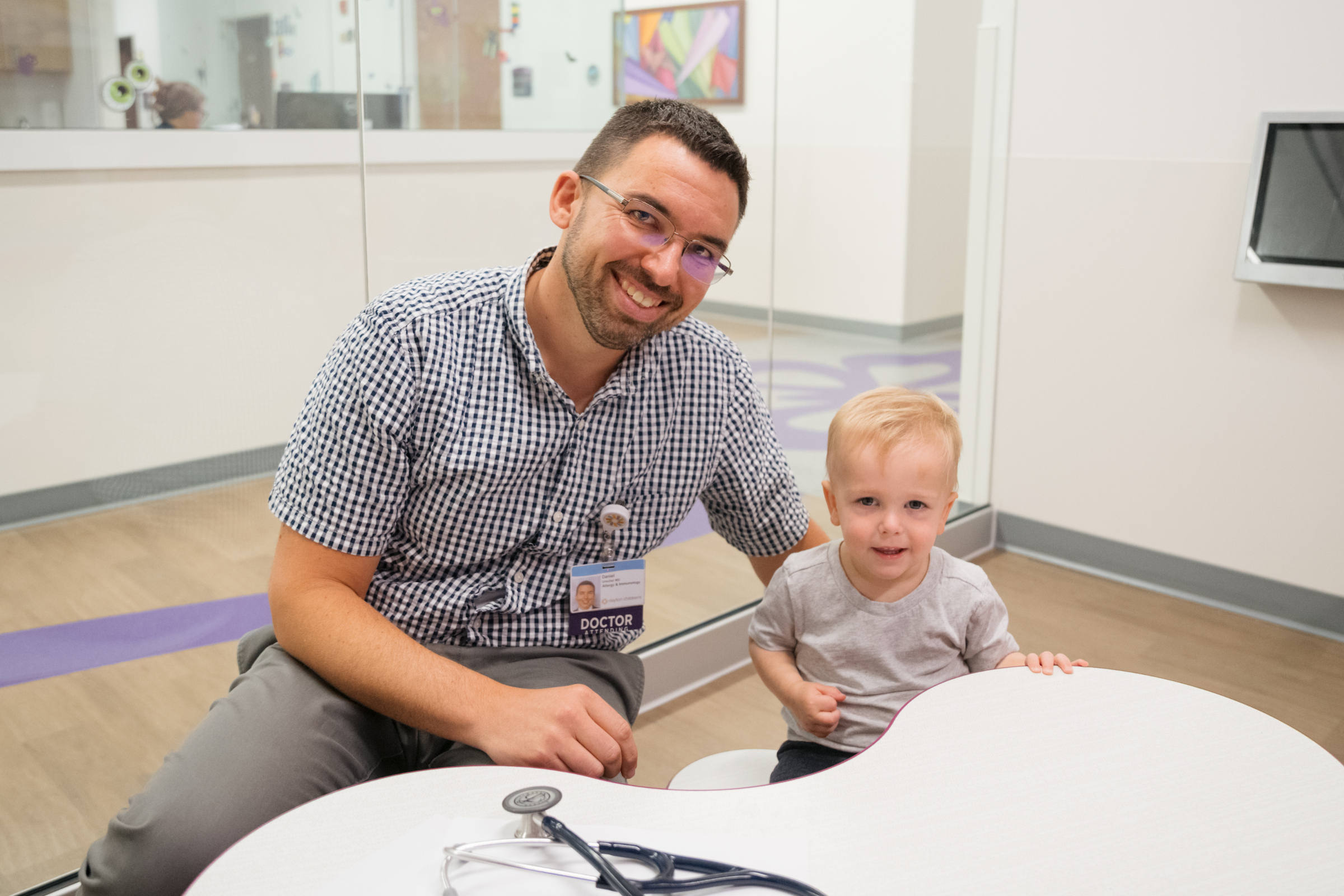 Toddler boy smiling with a male pediatric specialist in allergy clinic after a successful visit.