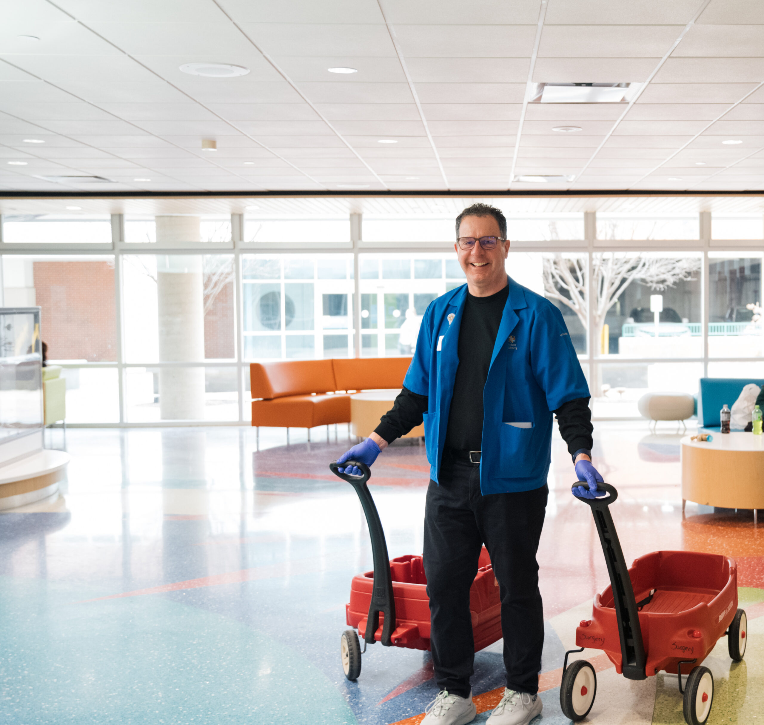 Male volunteer wearing blue volunteer coat, pulling two wagons