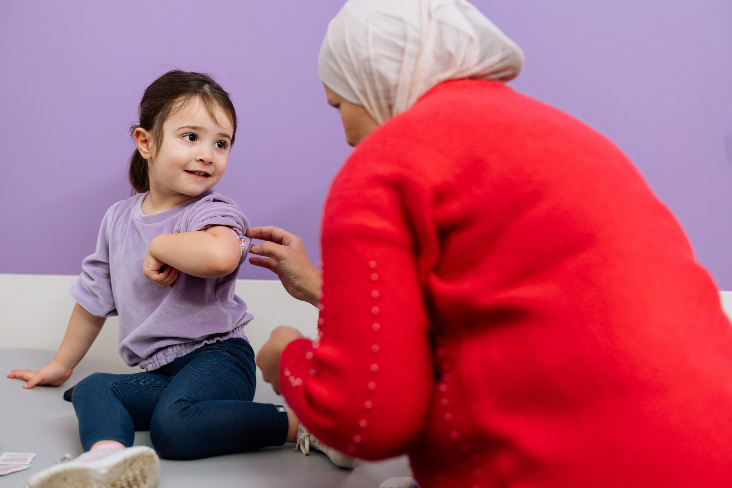 Dayton endocrinology provider in red sweater looking at young girl’s insulin patch after diabetes check up