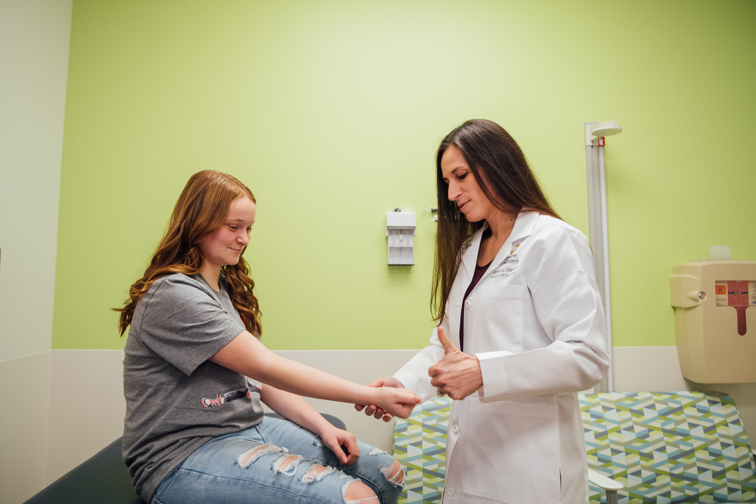 A female pediatrician performs hand exercise with a patient to test their flexibility. 