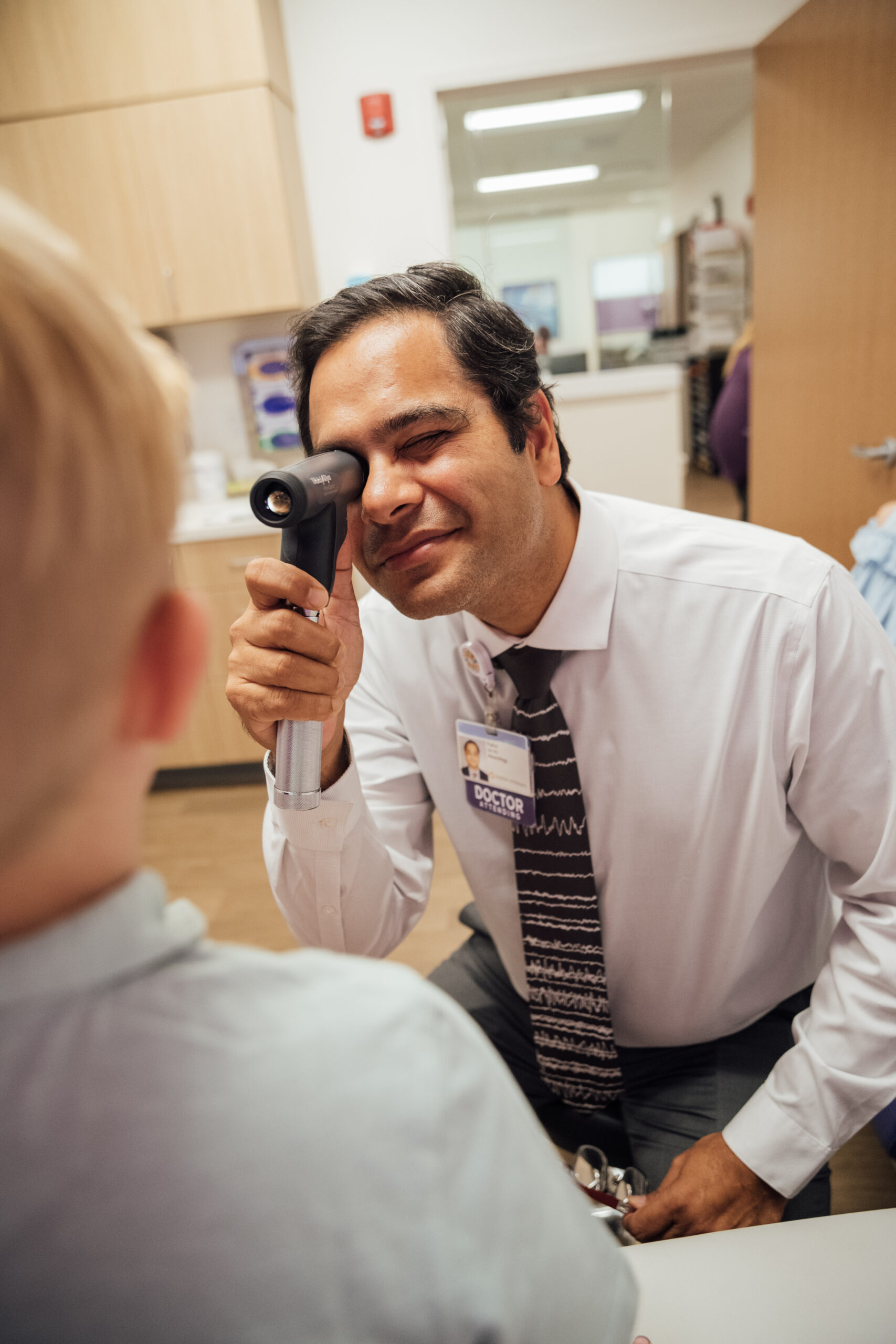 A pediatric neurologist shines a light into a patient’s eyes to see the reaction time of the pupils.