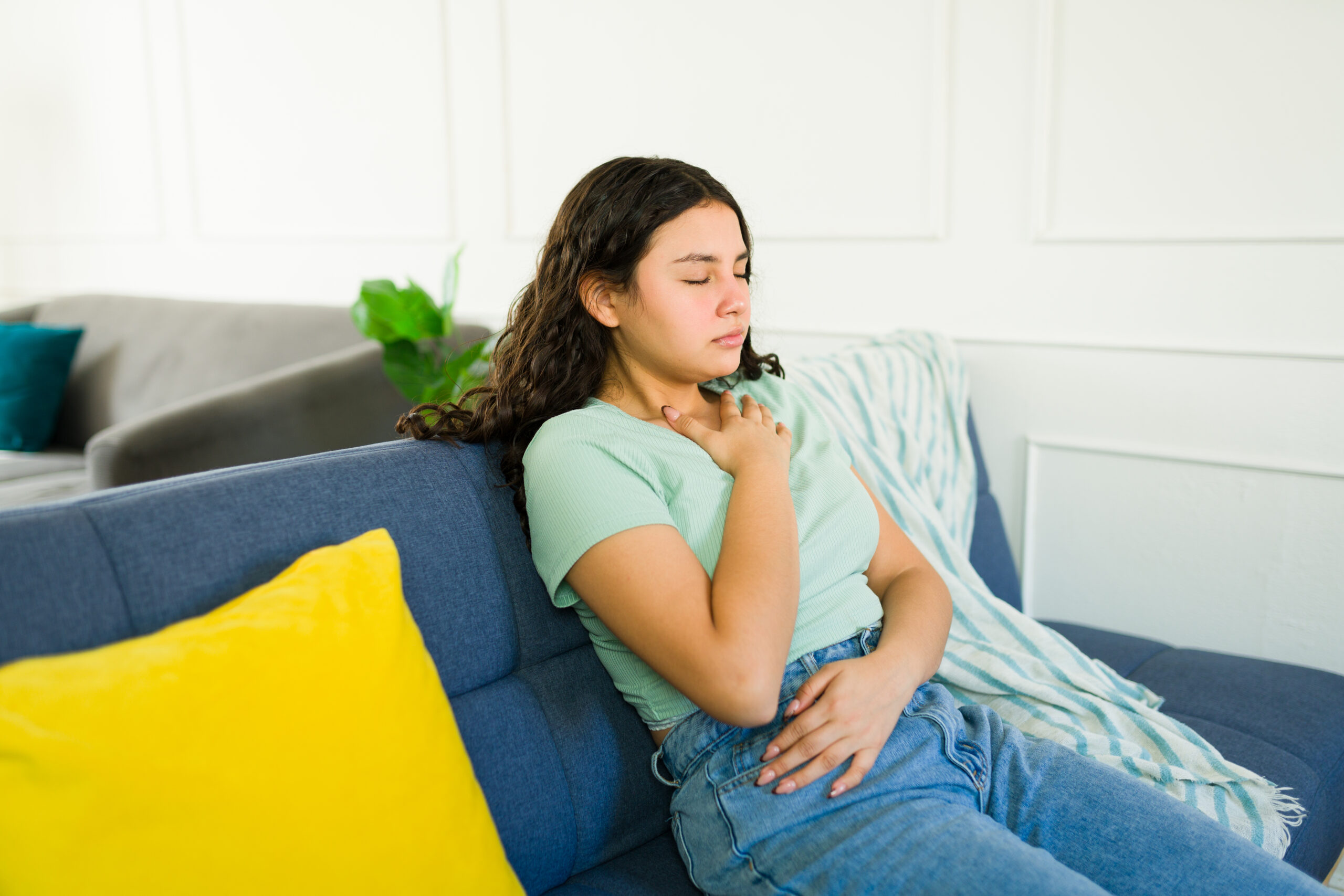 A teenager holds her chest gentle as it is difficult to breathe with her illness.