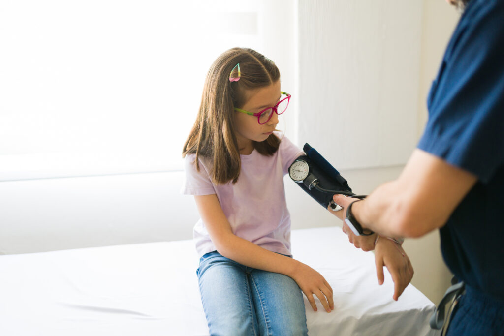 A young girl gets her blood pressure taken with a blood pressure cuff by a nurse. 