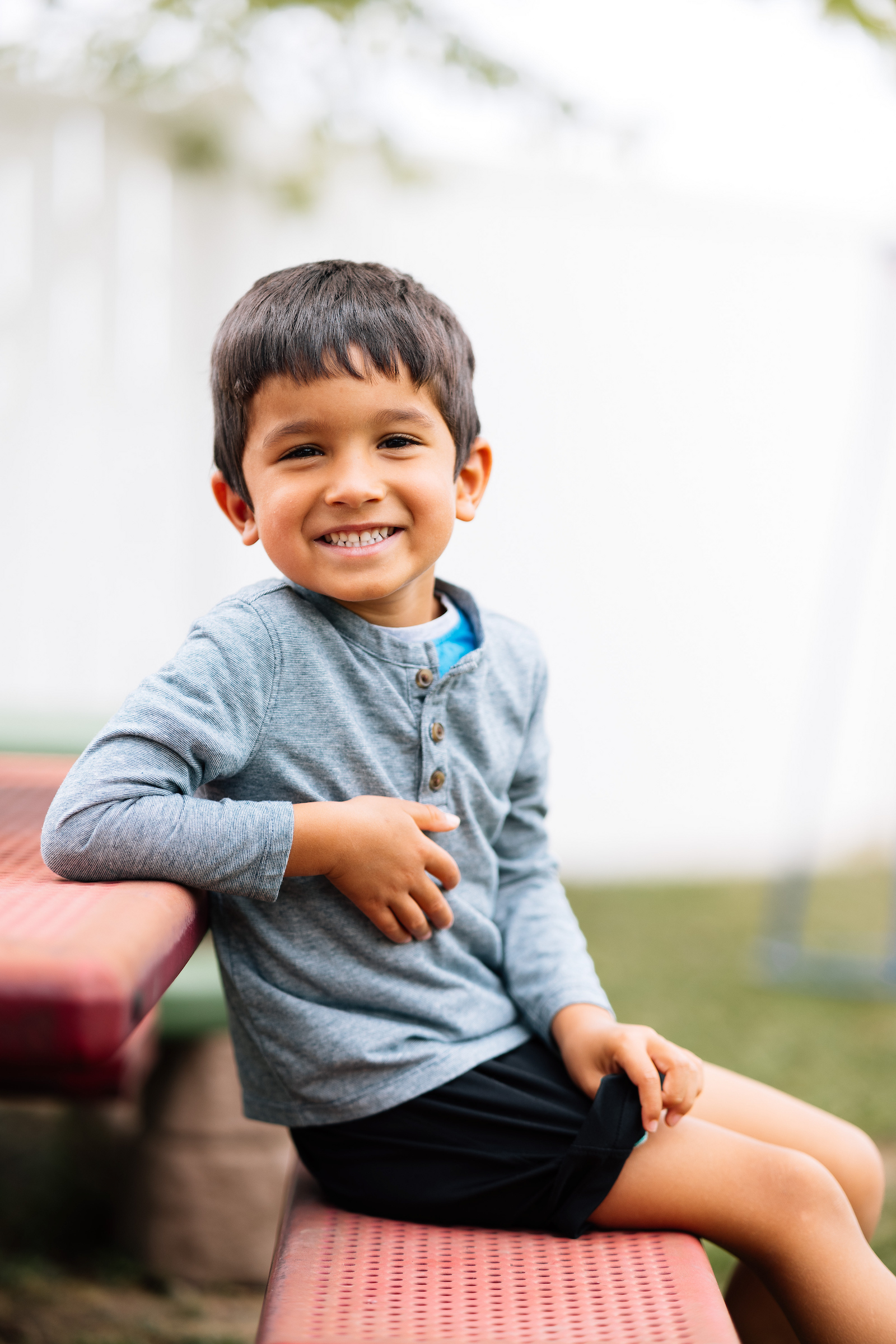 Young boy smiling sitting on bench while playing outside with his allergies under control