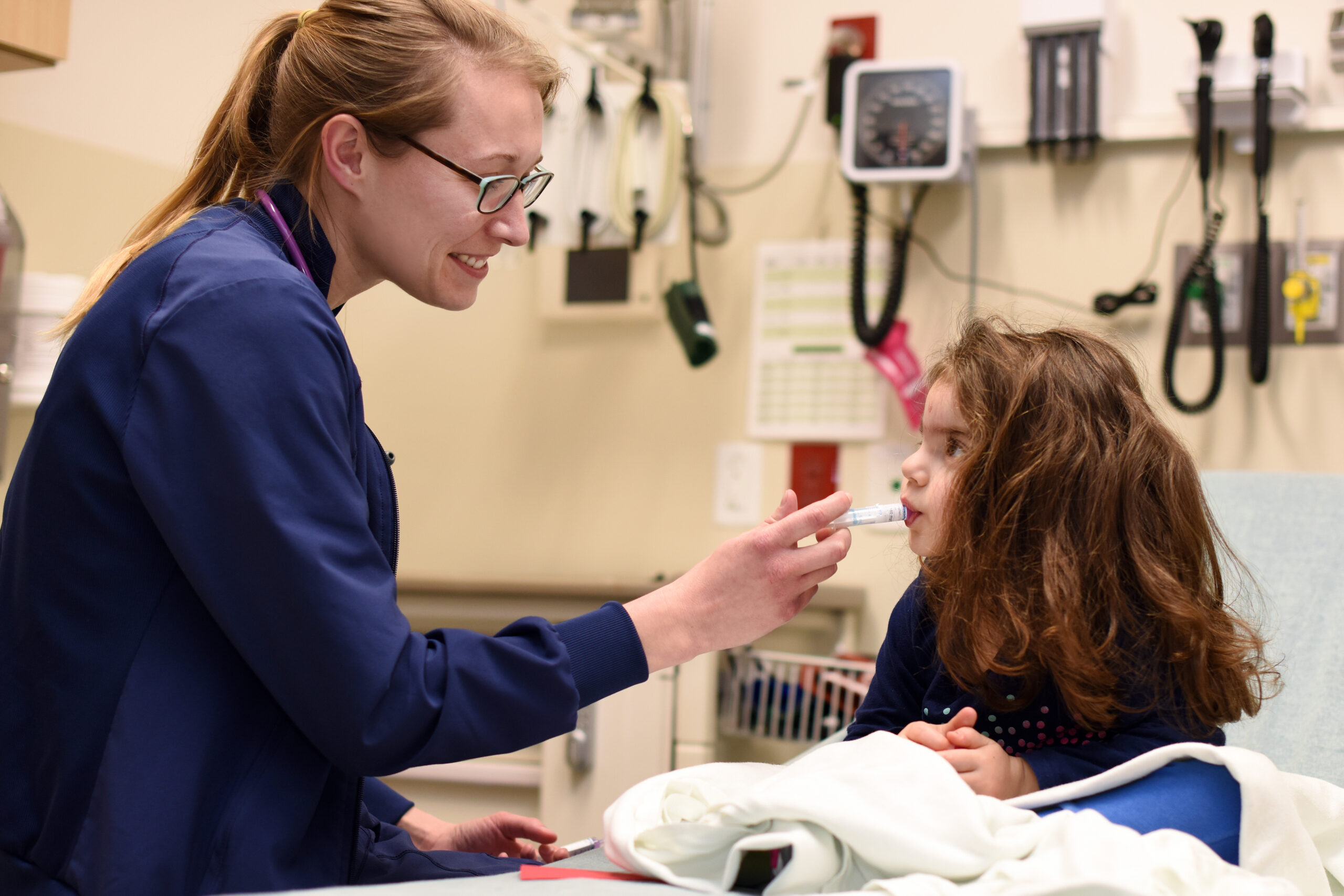 A nurse administers oral medication to a patient in a hospital bed.