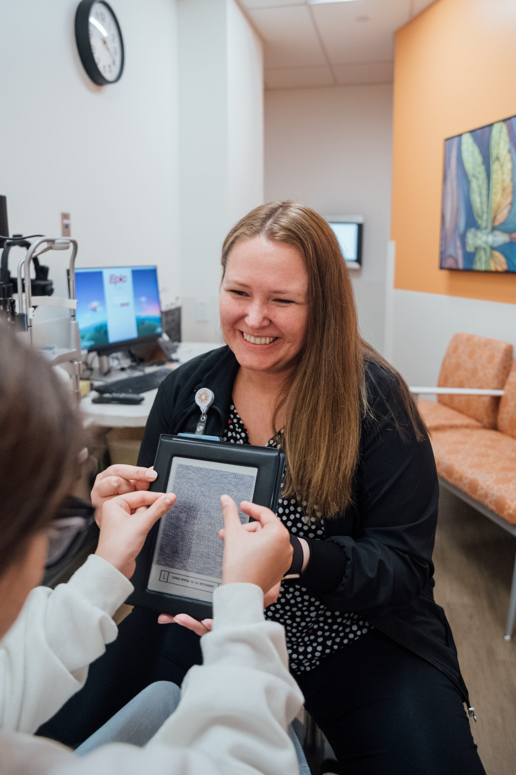 A female pediatric ophthalmologist uses a 3D vectograph to test a patient's vision.