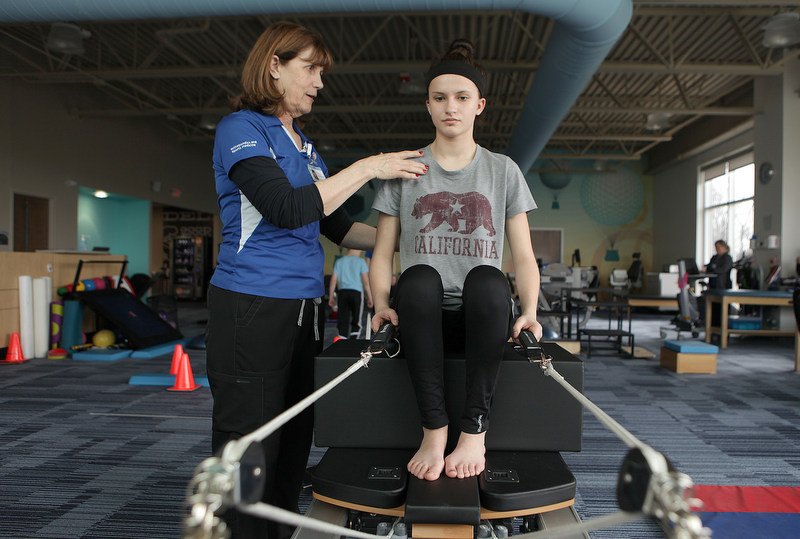 A pediatric orthopedic therapist works with a teen patient to help stretch and release some of their pain.