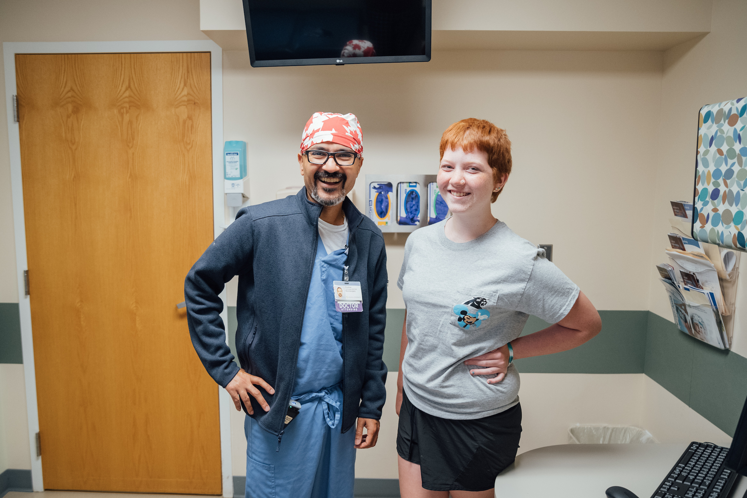 Physical medicine doctor standing with a smiling teenage patient during a follow-up visit at a rehabilitation clinic.