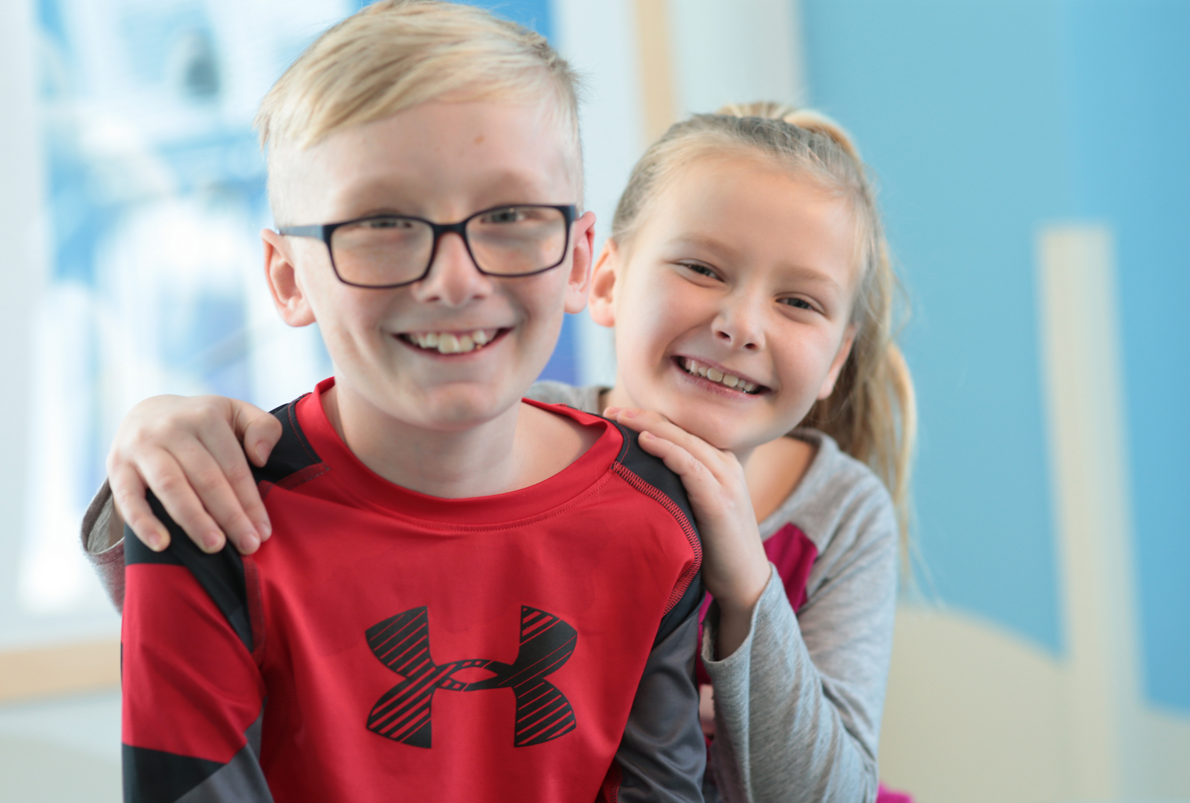 Young boy with glasses and young girl smile and pose for a picture during pediatric cardiology appointment