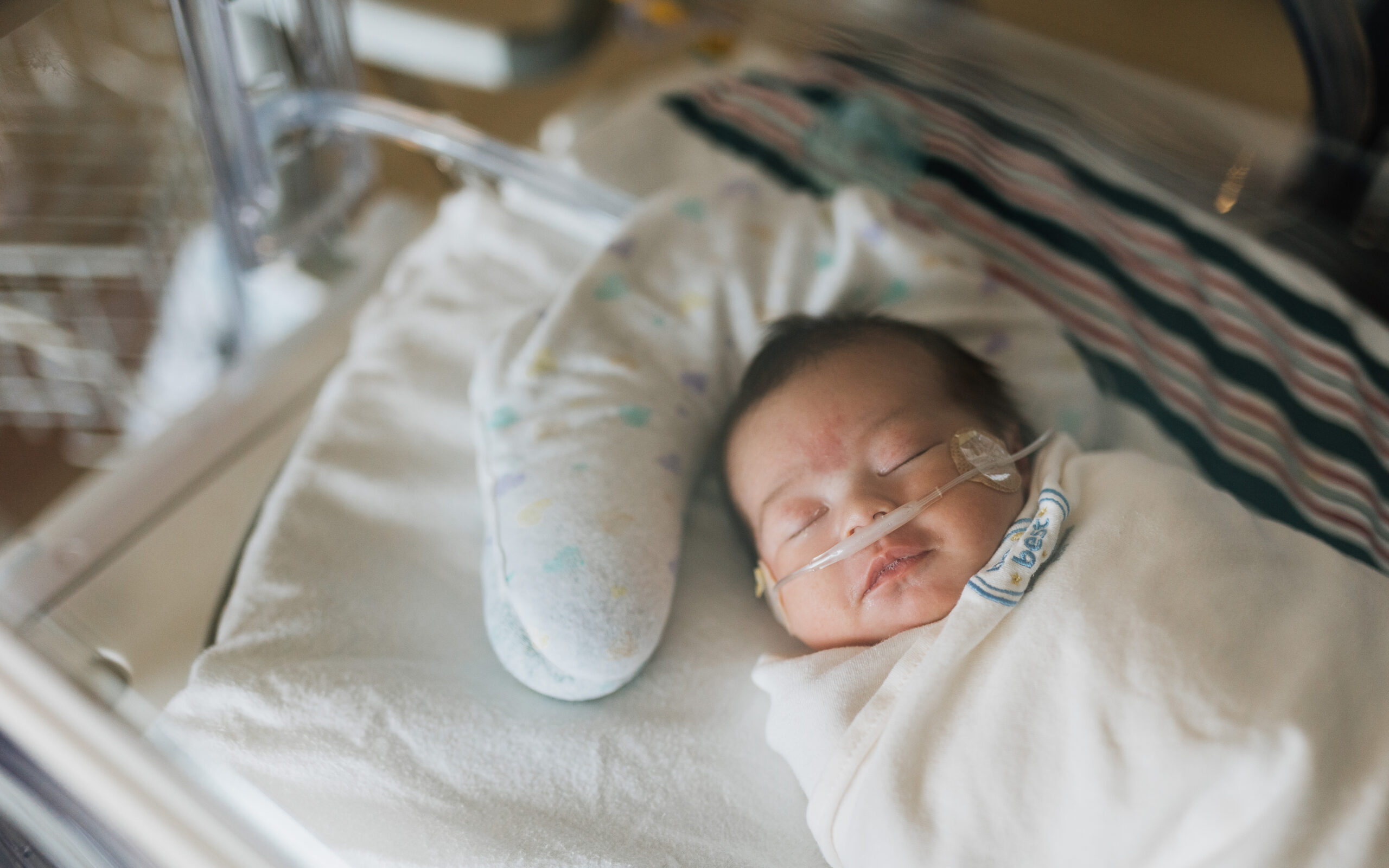 newborn baby boy swaddled and sleeping in hospital bassinet awaiting circumcision