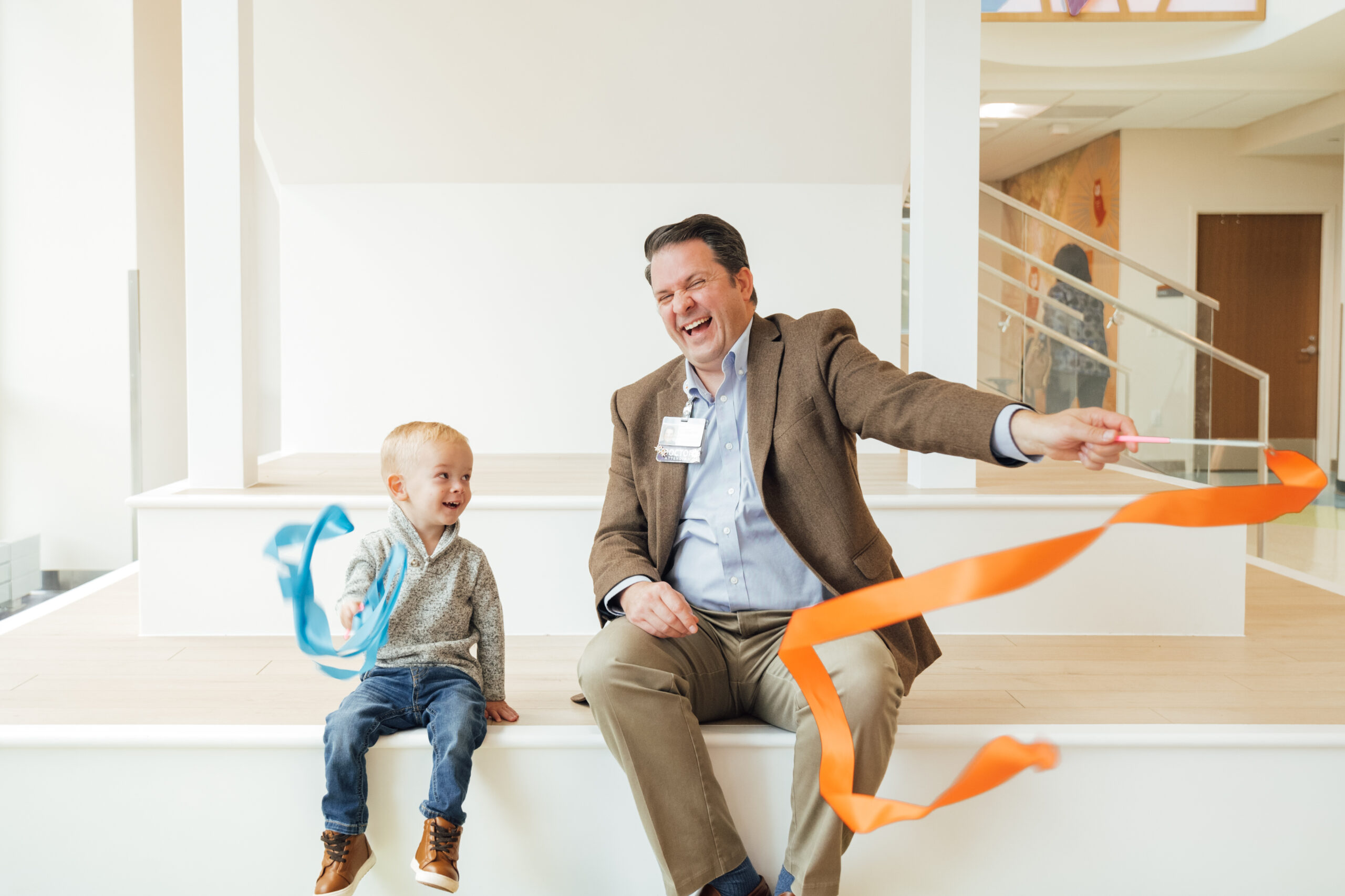 Dr. Kelly Sandberg, Pediatric Gastroenterologist playing with ribbons, laughing with young boy patient