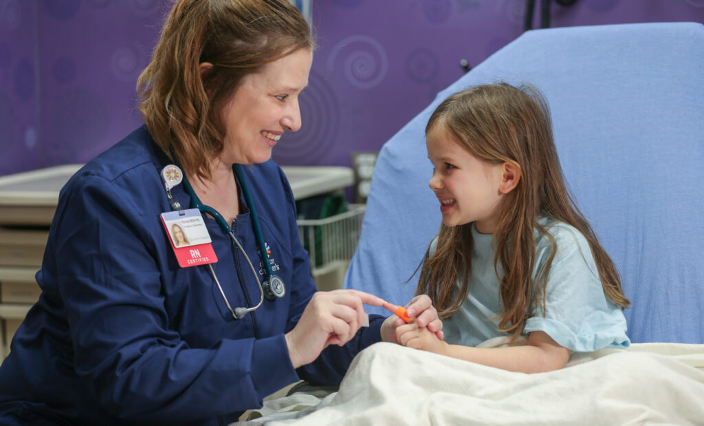 A Dayton Children’s ER nurse wraps a little girl's finger in a bandaid.