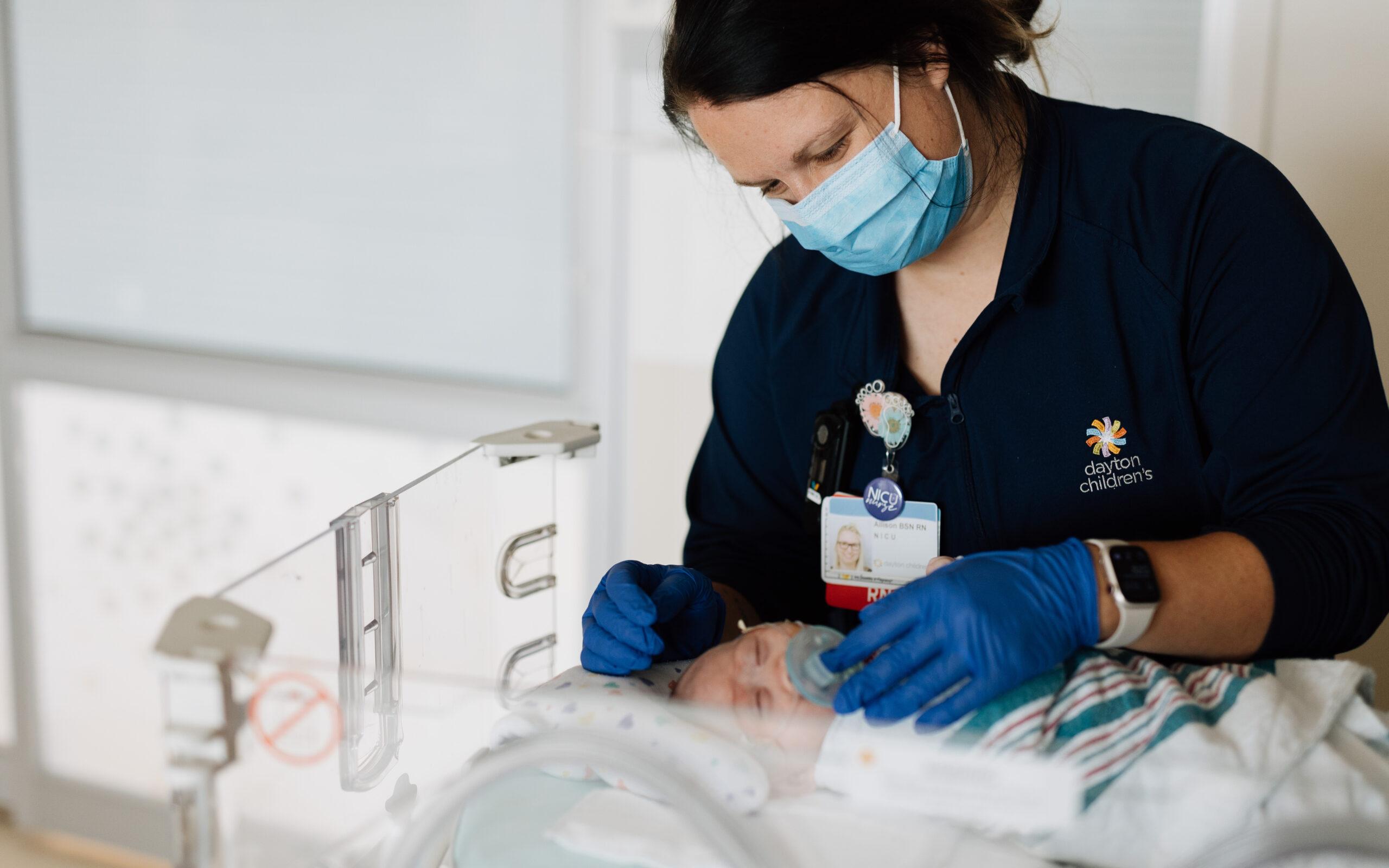 A nurse checks on a NICU baby, calming them down with their pacifier. 