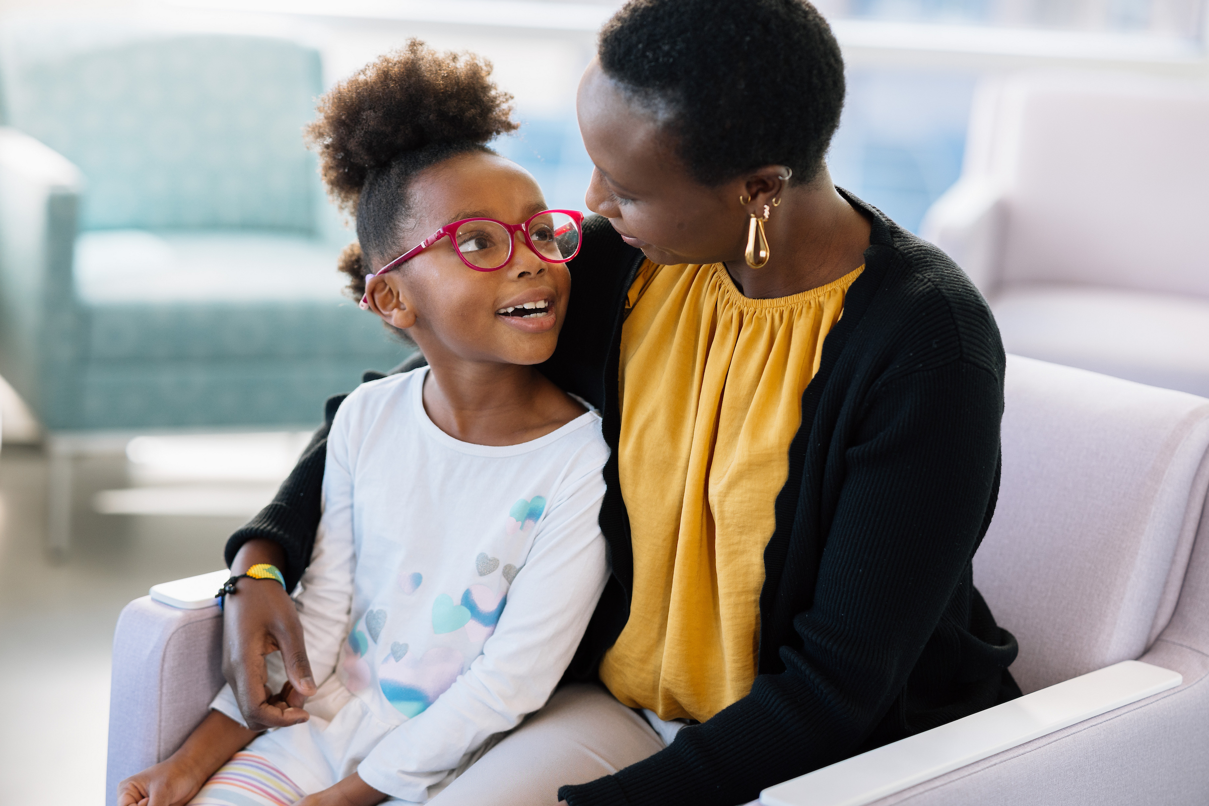 Young child sitting with family in a bright waiting area at Dayton Children’s Hospital.