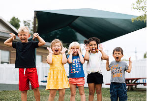 A group of smiling children participate in an outdoor community event, symbolizing outreach and impact featured in the community benefit report.