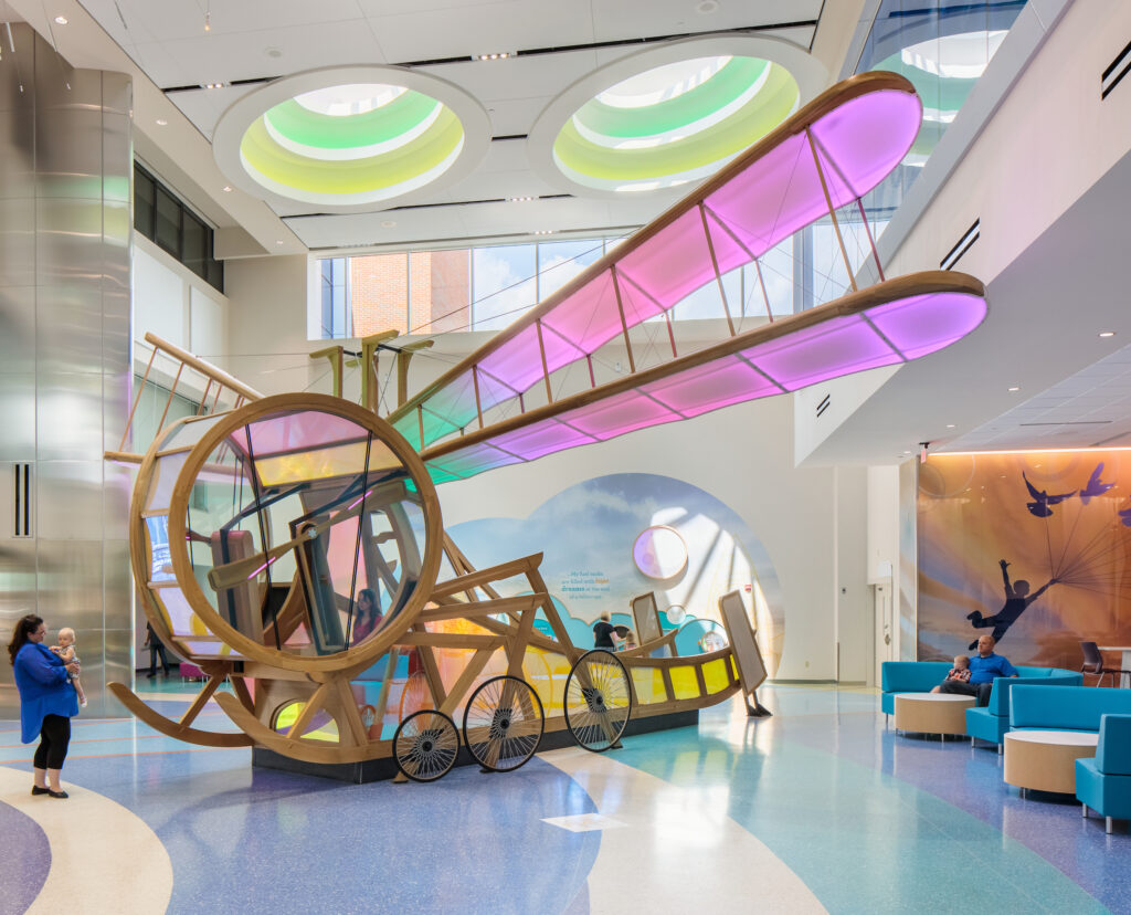 A colorful, dragonfly-shaped play structure with translucent wings sits in a bright, modern space at Dayton’s Children's Hospital. 