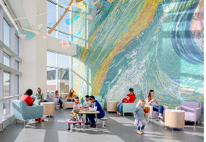 Families gather in a colorful hospital lobby with a large mural, showcasing the spaces and care made possible through donor support.