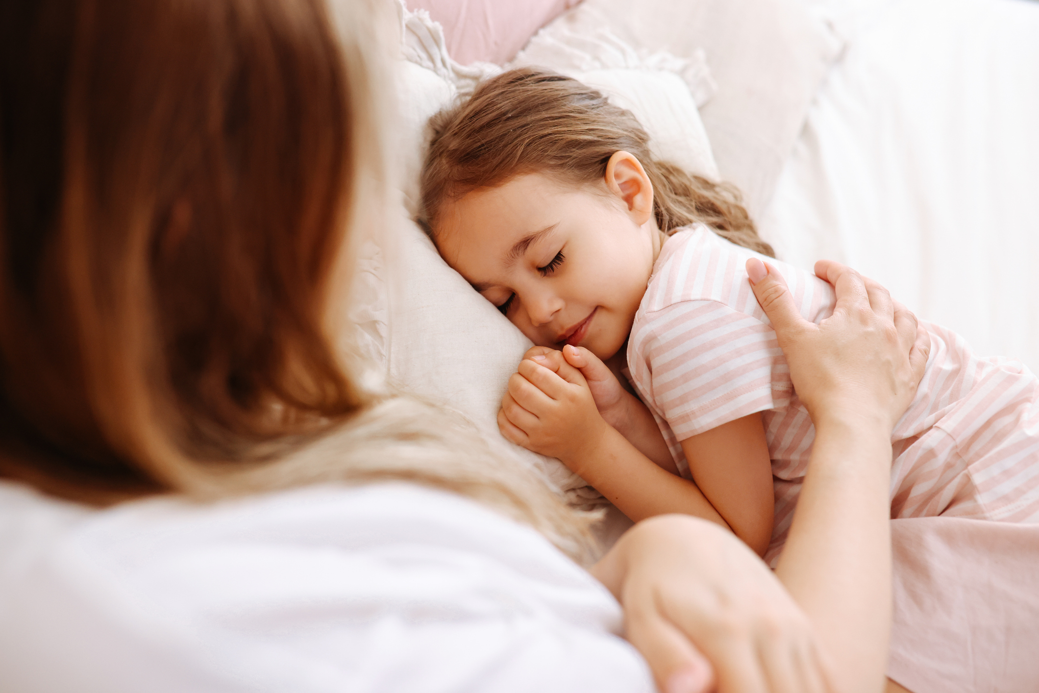 Mother comforting her daughter while she sleeps with a hand on her back as the daughter is controlling her obstructive sleep apnea