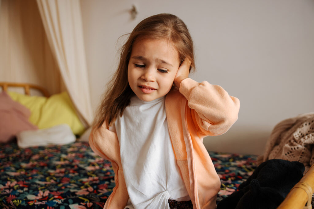 Girl holding ear in pain due to possible frequent ear infections