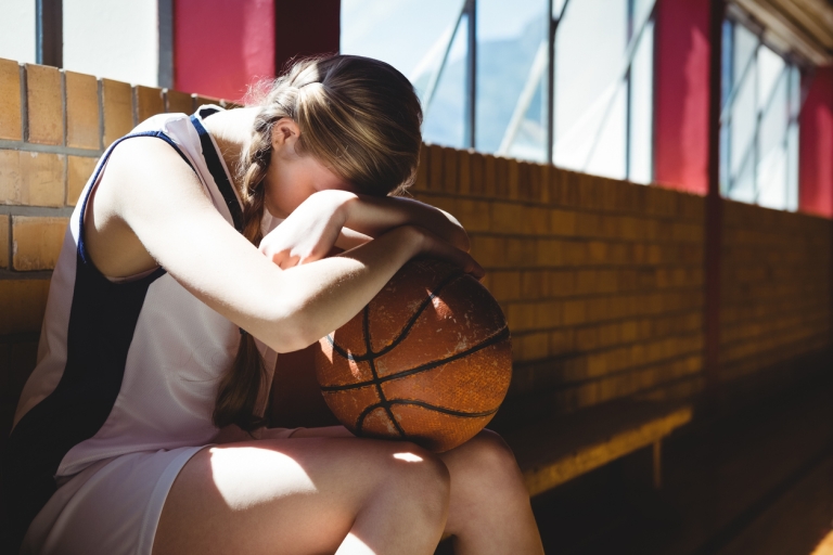Sad girl holding a ball while going through a difficult moment.