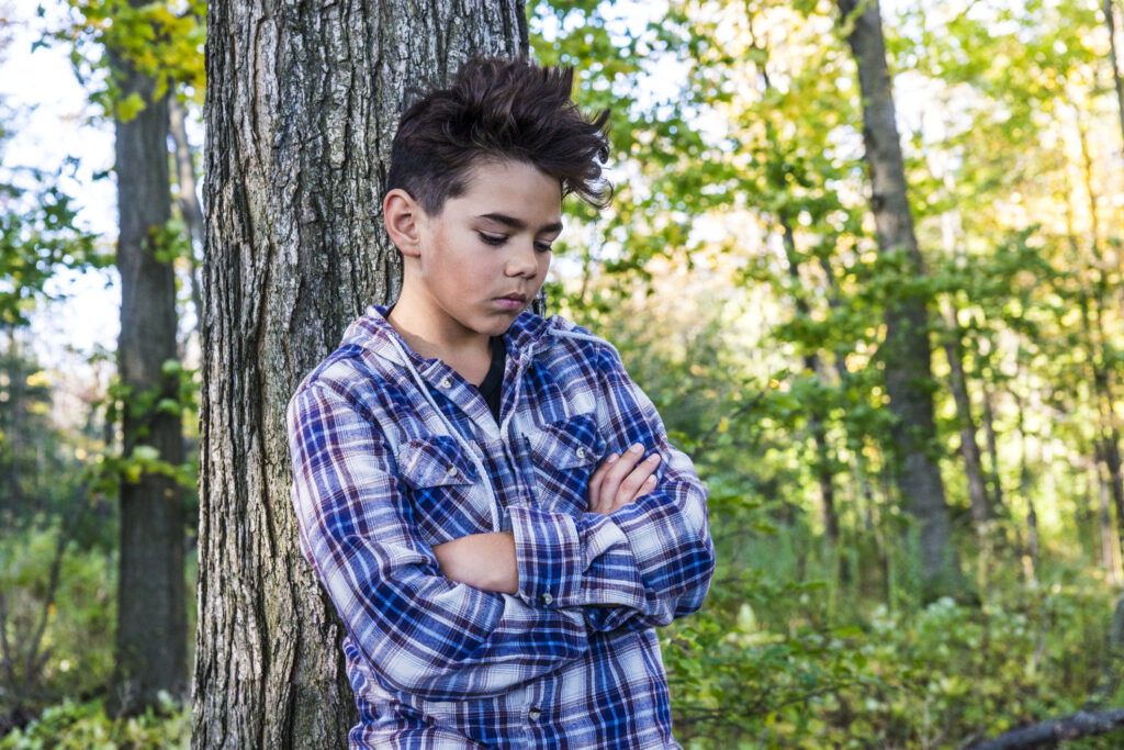 Handsome preteen boy serious and pensive in a forest.