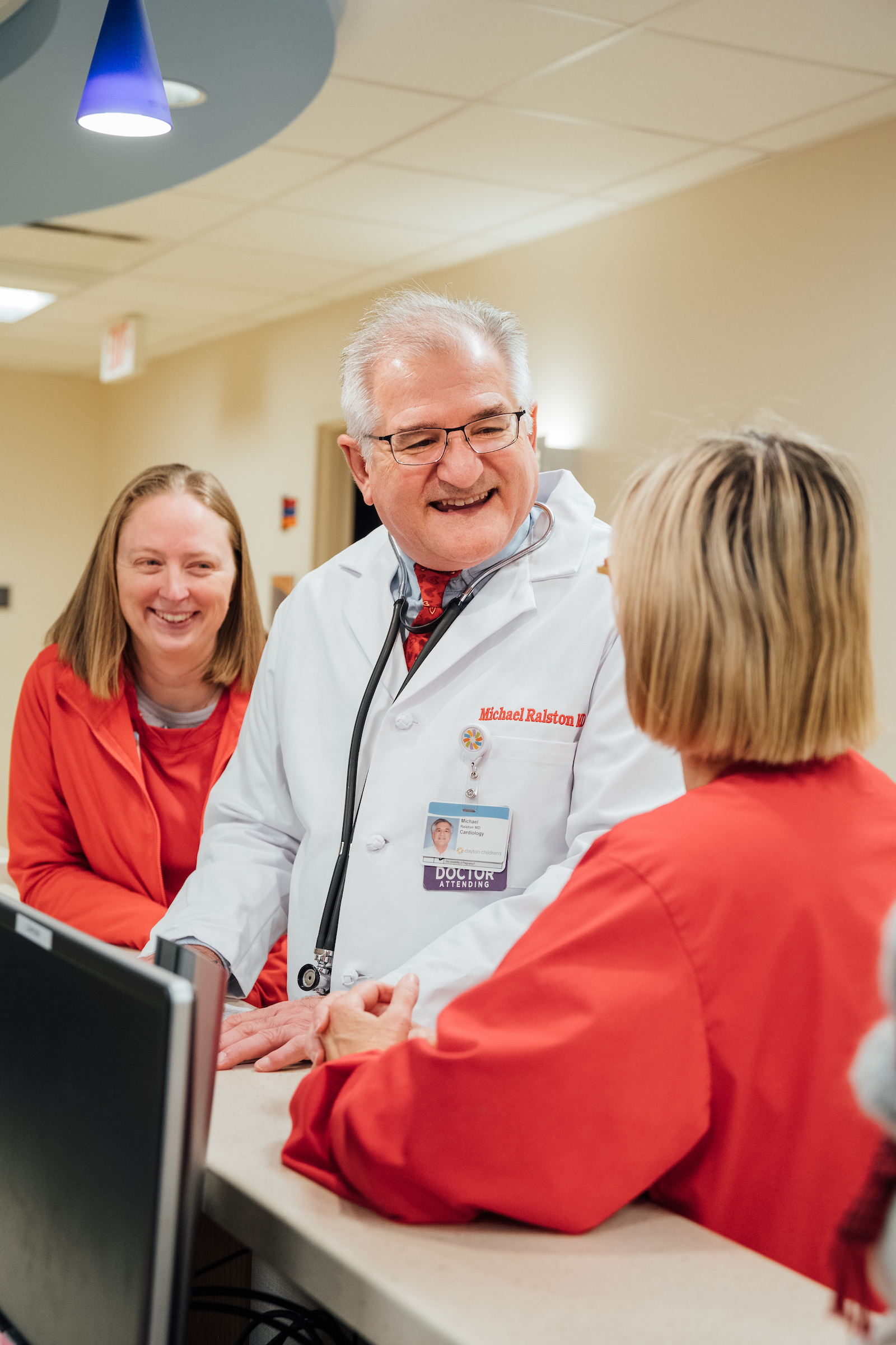 Doctor and nurses talking and laughing at a nurses station enjoying their day at work.
