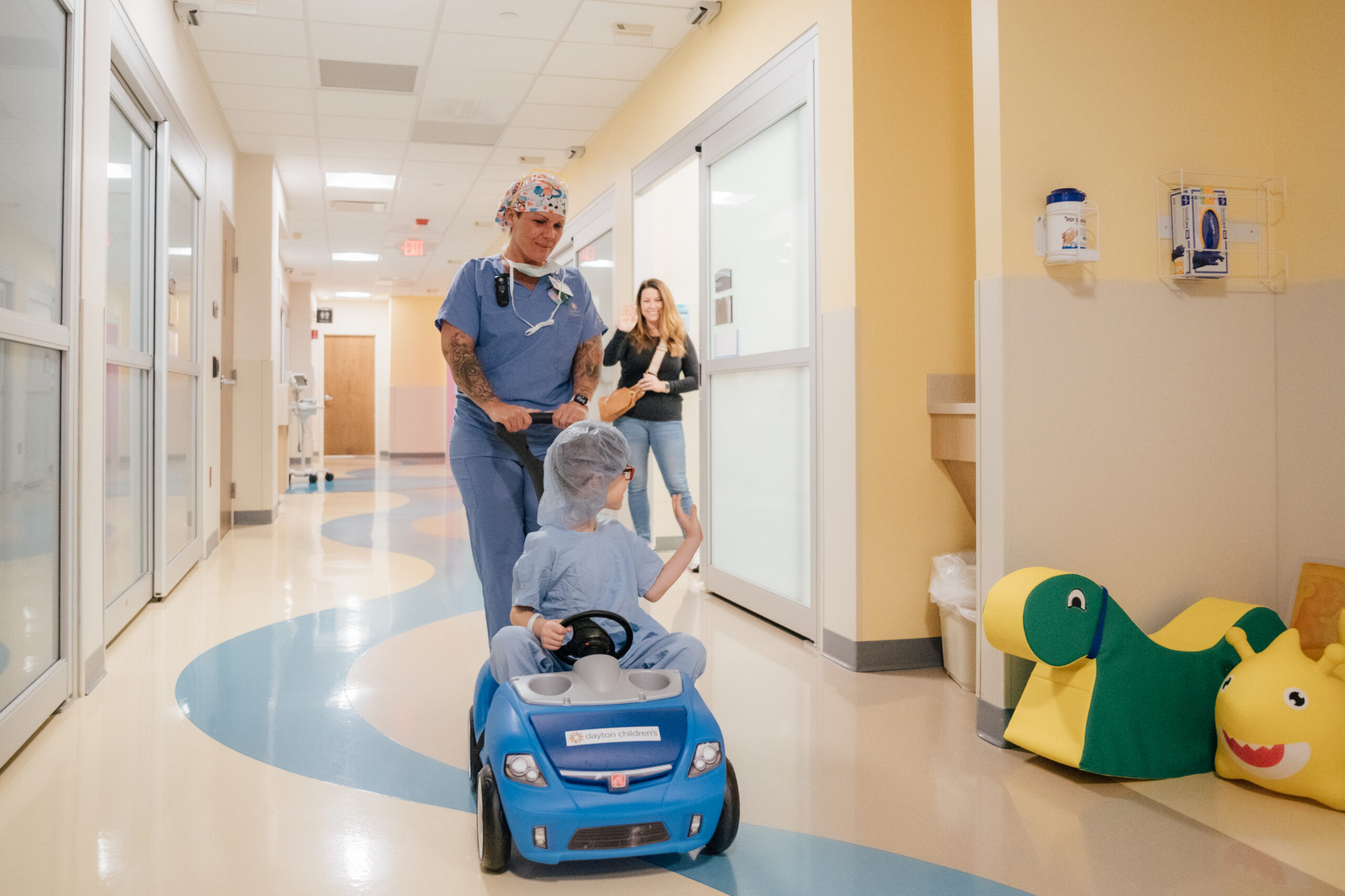 Young boy patient rides in push car having fun as he rides to the operating room.