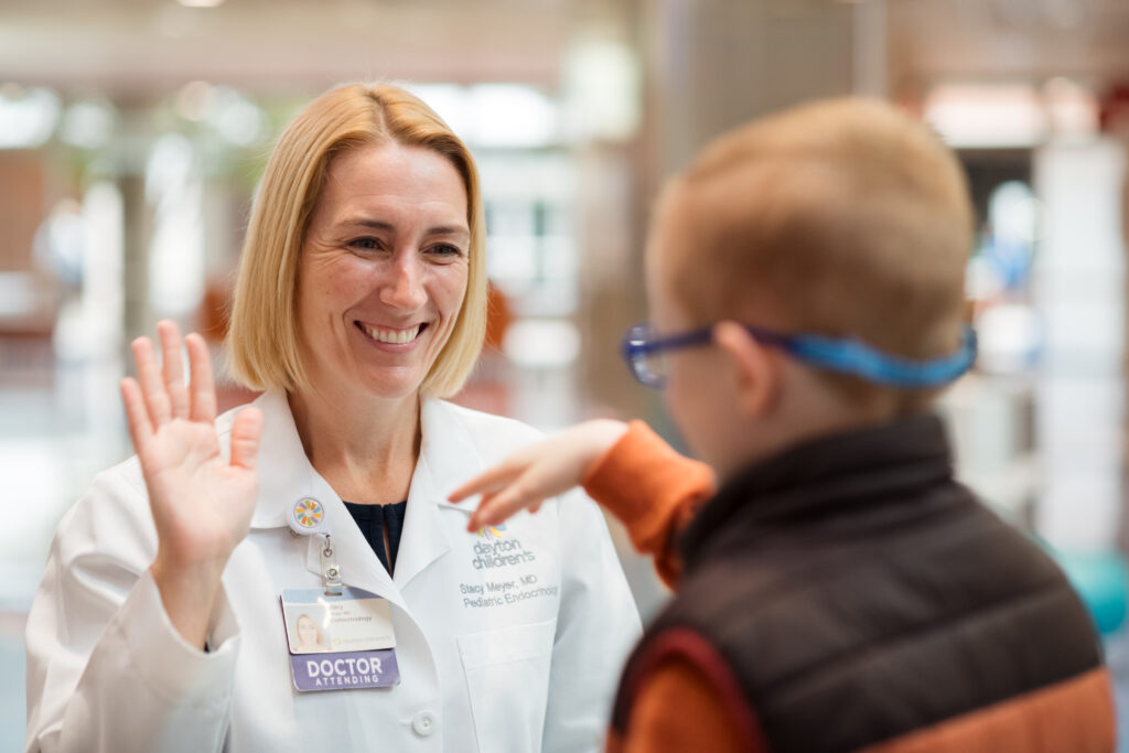 A Dayton Children’s physician high fives a male patient in the lobby.